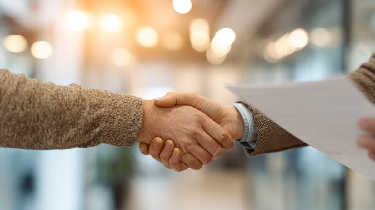 Coach en cliënt schudden handen na ondertekening van het coachcontract