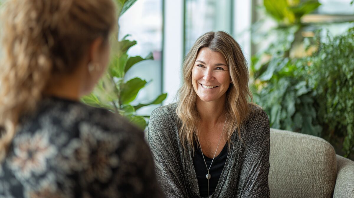 Coach in supportive one-on-one wellness sessie met employee in quiet office wellness space, compassionate personalized care