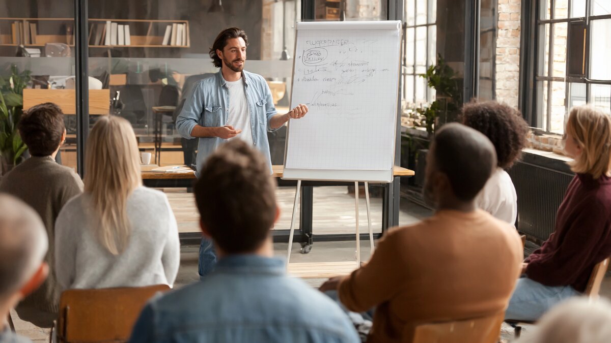 Coach geeft workshop presentatie aan groep met whiteboard