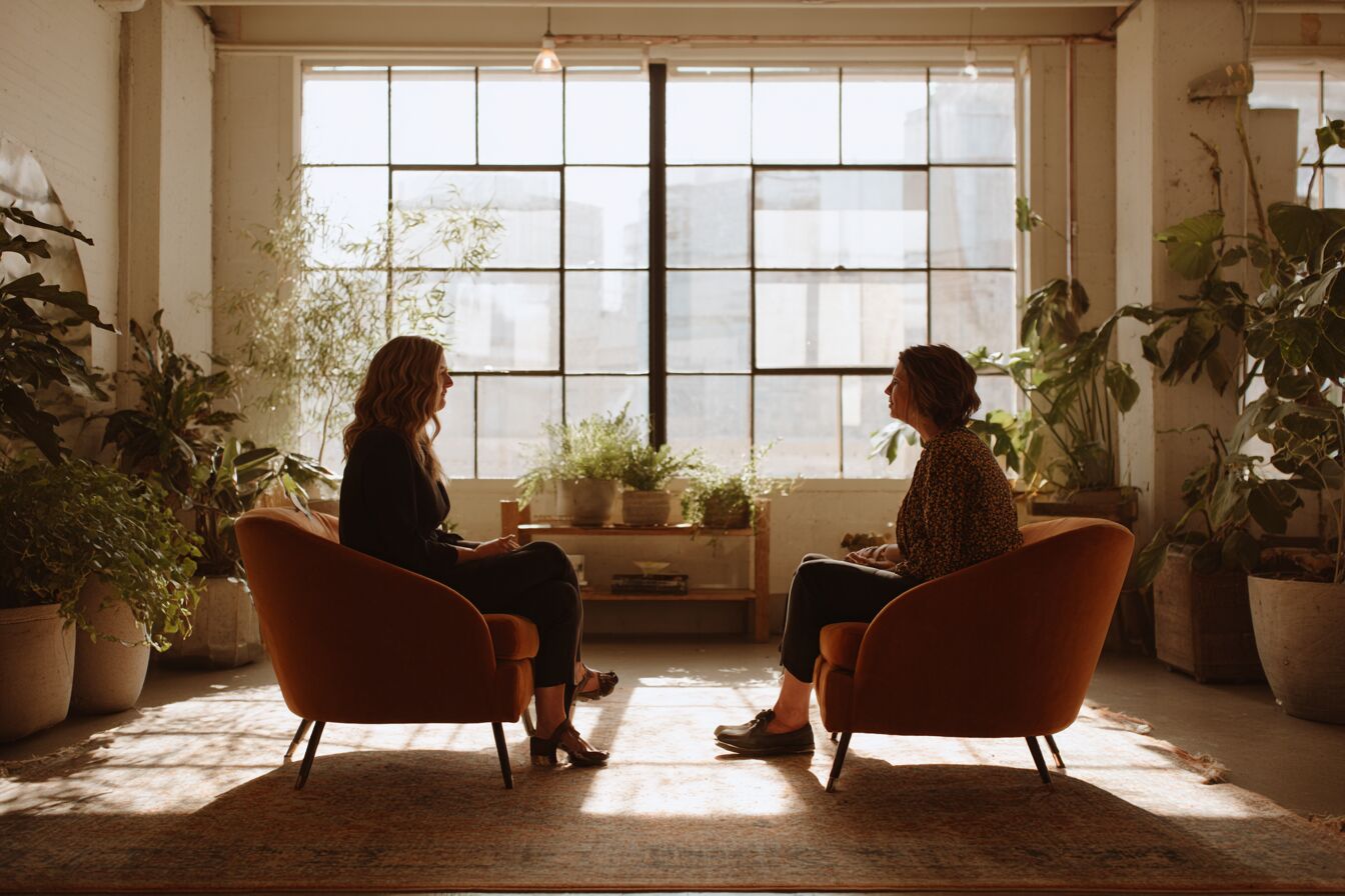 Coaching sessie met twee mensen in loft-ruimte met natuurlijk licht en planten
