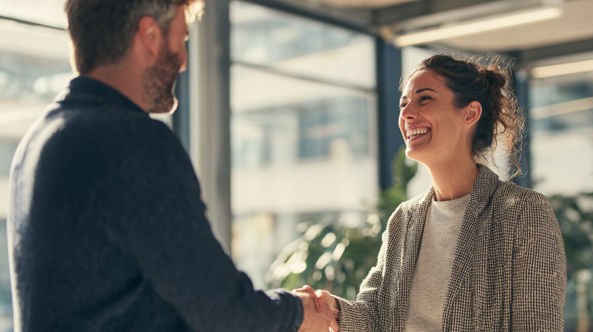 Coach congratuleert successfully transitioned client met warm handshake, genuine celebration van new job placement